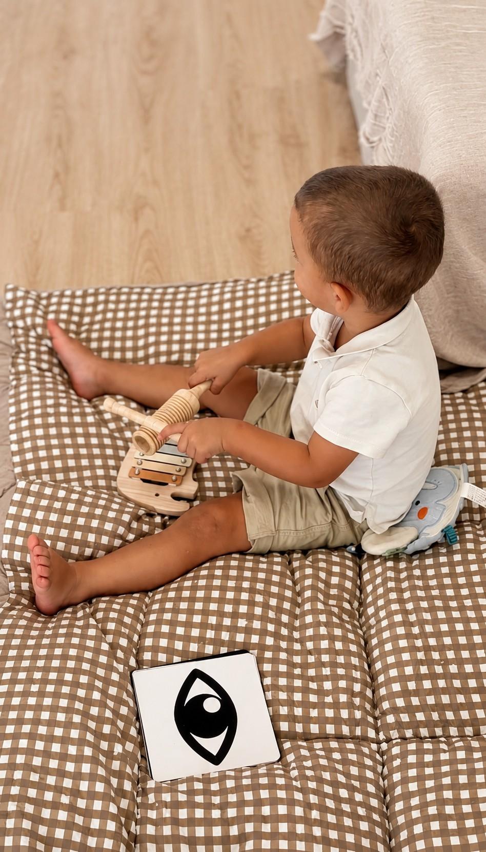 Un niño juega sentado sobre una colchoneta de cuadros