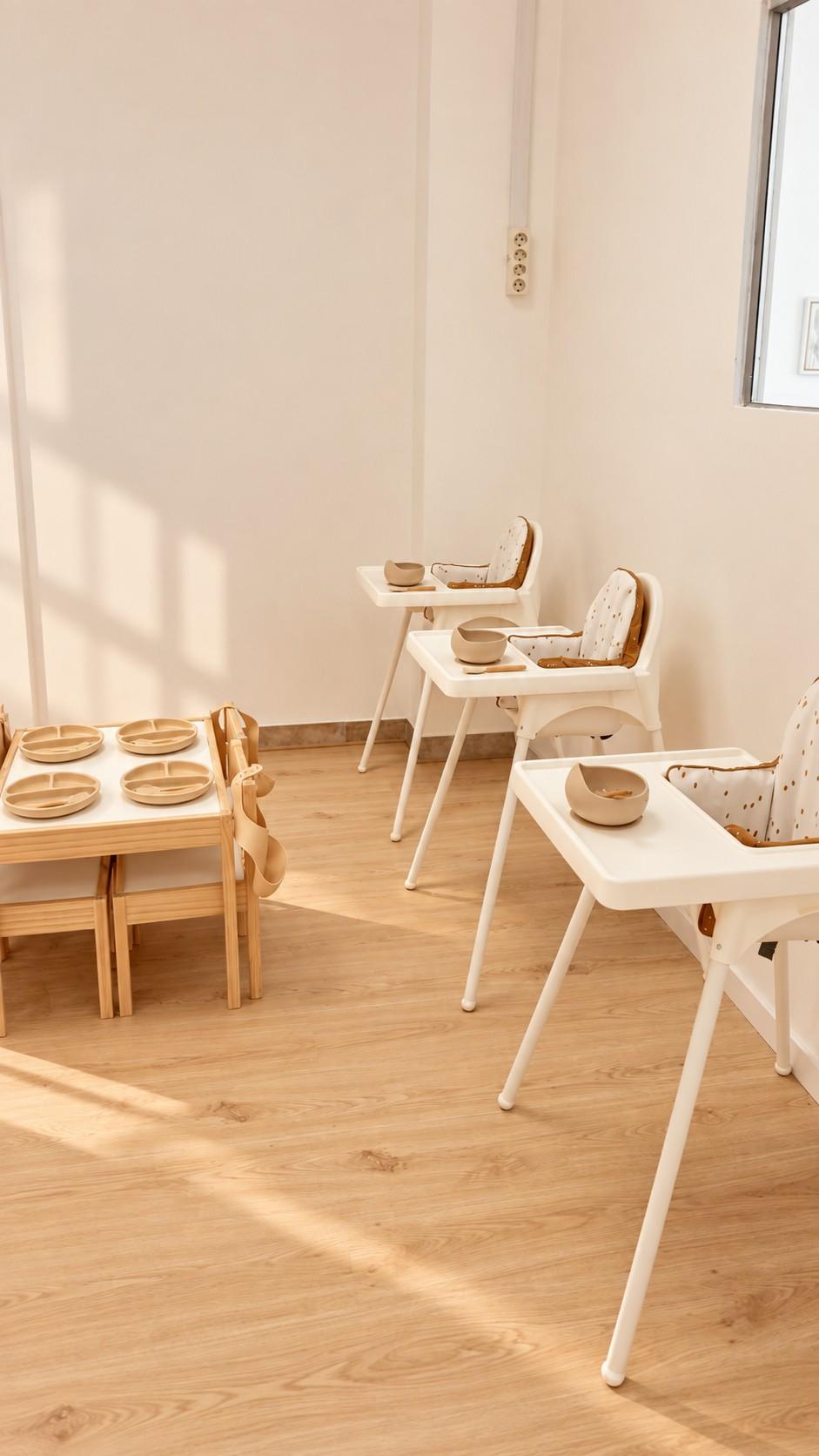 Zona de comidas luminosa con tronas y mesitas de madera